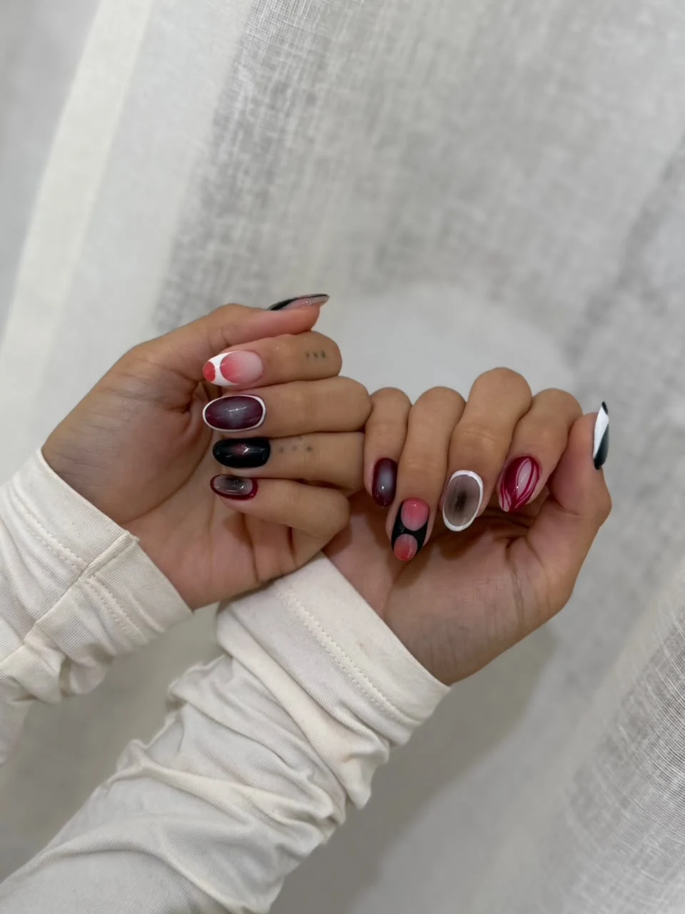 Diseño de uñas largas con formas circulares en rosa y vino.